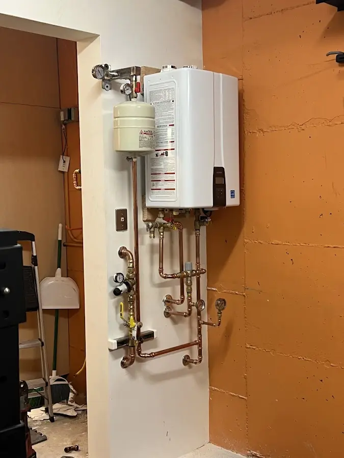 Plumbing technician inspecting water heater connections in Westgate